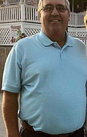 Man wearing a blue shirt smiling in front of a restaurant